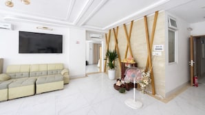 Una hall moderna con un divano, una TV, un ventilatore e una parete decorativa.