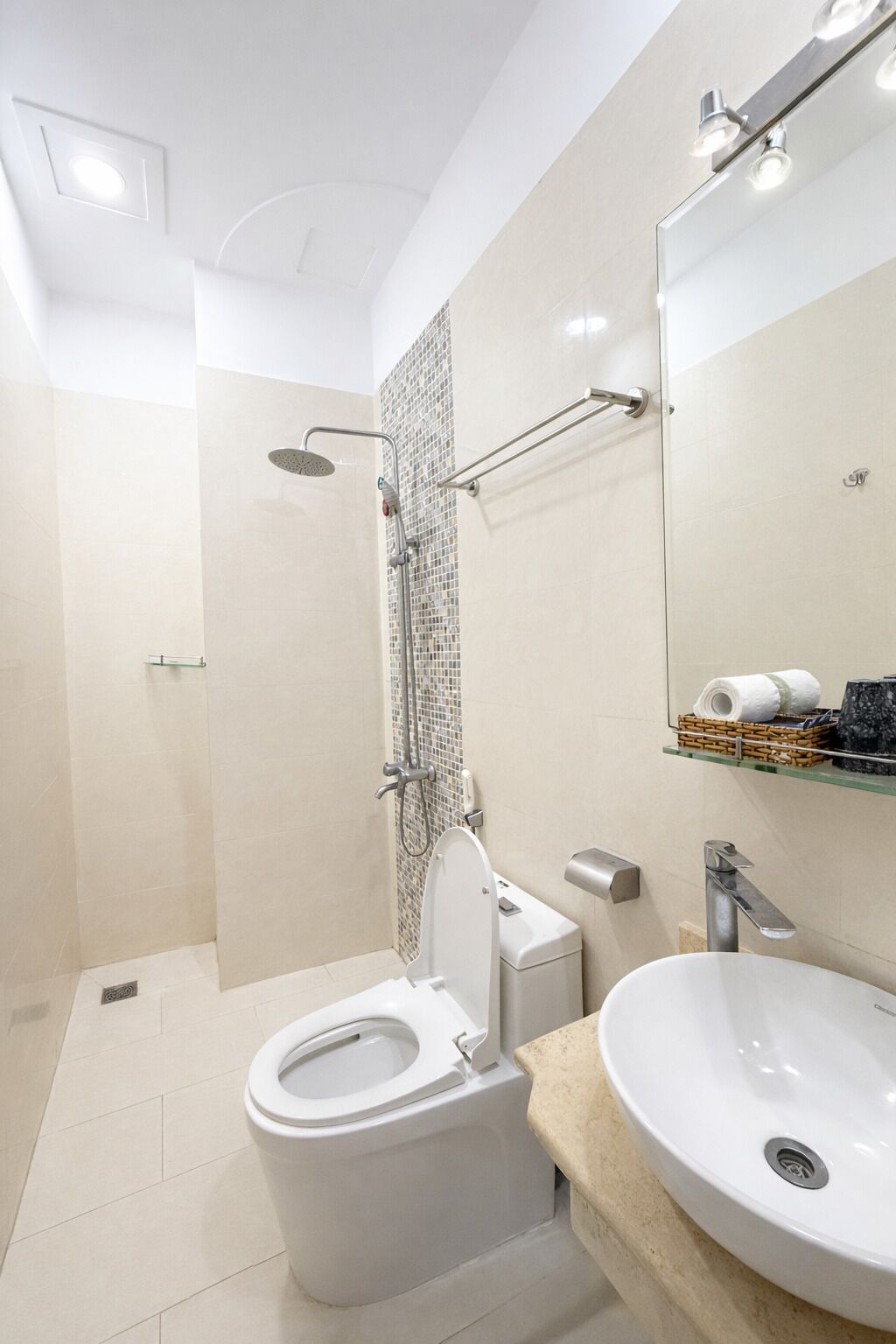 Un baño moderno con inodoro, lavamanos, ducha y espejo.
