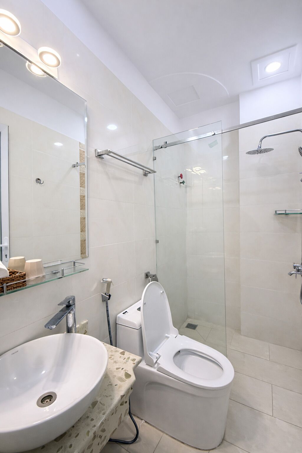 A modern bathroom with a glass-enclosed shower, a white sink, and a toilet.