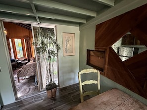 Une pièce avec un plafond en bois, une plante en pot, un tableau encadré et une chaise.