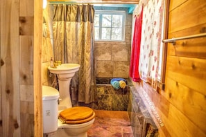A small bathroom with a wooden floor, a toilet, a sink, and a window. - Cozy Unique Cottage for a Peaceful Escape in Nature in Topanga, California (Topanga)