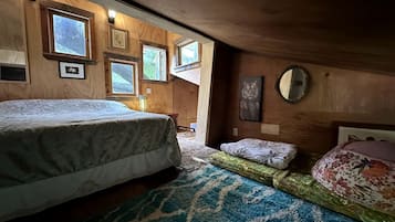 A bedroom with a bed, a small sofa, a rug, and framed pictures on the wall.
