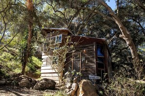 Une cabane en bois entourée d’arbres, sur laquelle on peut lire l’inscription « PAYS DES MERVEILLES ».