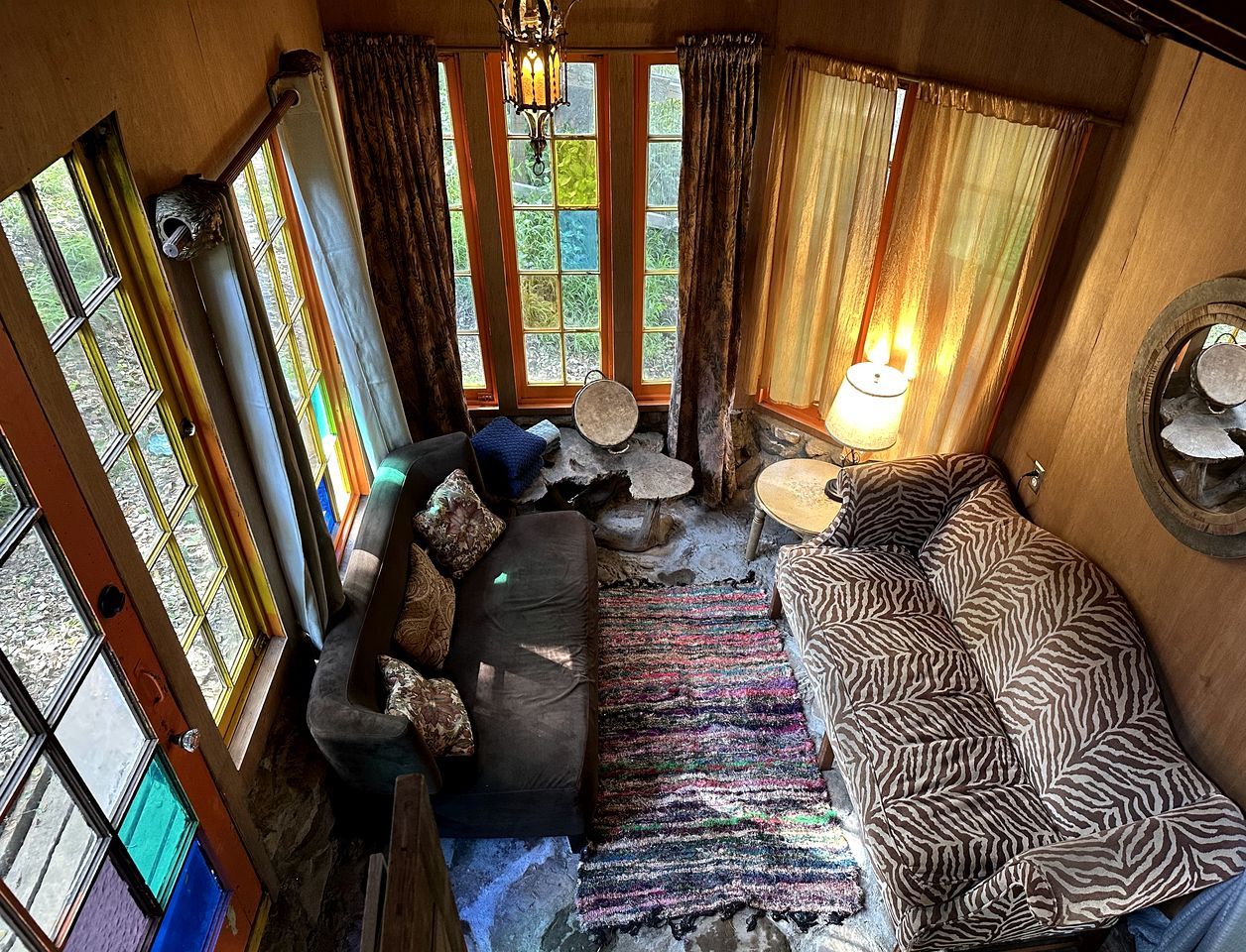 Una habitación acogedora con un sofá, un tapete estampado y una lámpara.