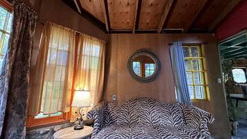 Une pièce chaleureuse avec un canapé à motifs zébrés, un miroir rond et une petite table sur laquelle se trouve une lampe.