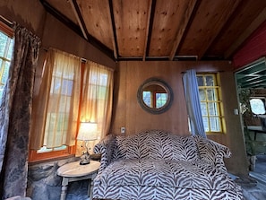 A cozy room with a zebra-patterned sofa, a round mirror, and a small table with a lamp.