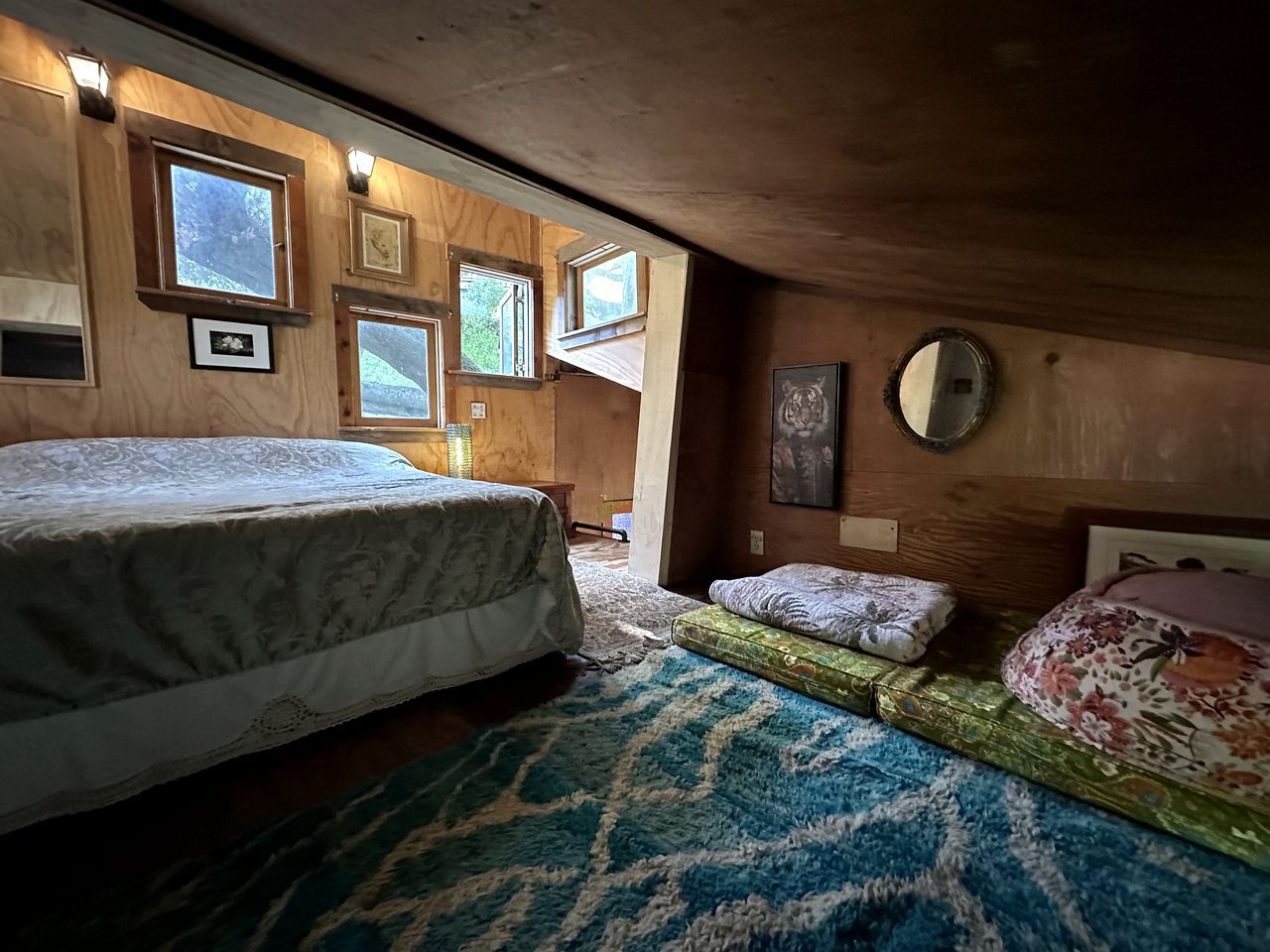 A bedroom with a bed, a small sofa, a rug, and framed pictures on the wall.