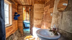 Et badeværelse i en træhytte med toilet, håndvask og et vindue.
