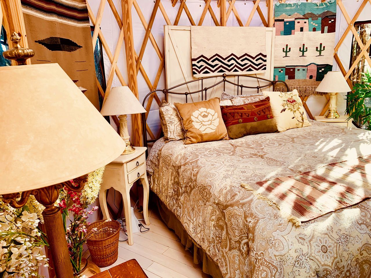A bedroom with a bed, two bedside tables, a lamp, and a wall with artwork.