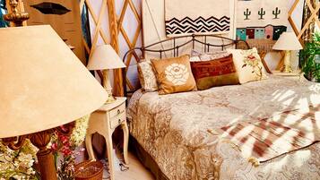 A bedroom with a bed, two bedside tables, a lamp, and a wall with artwork.