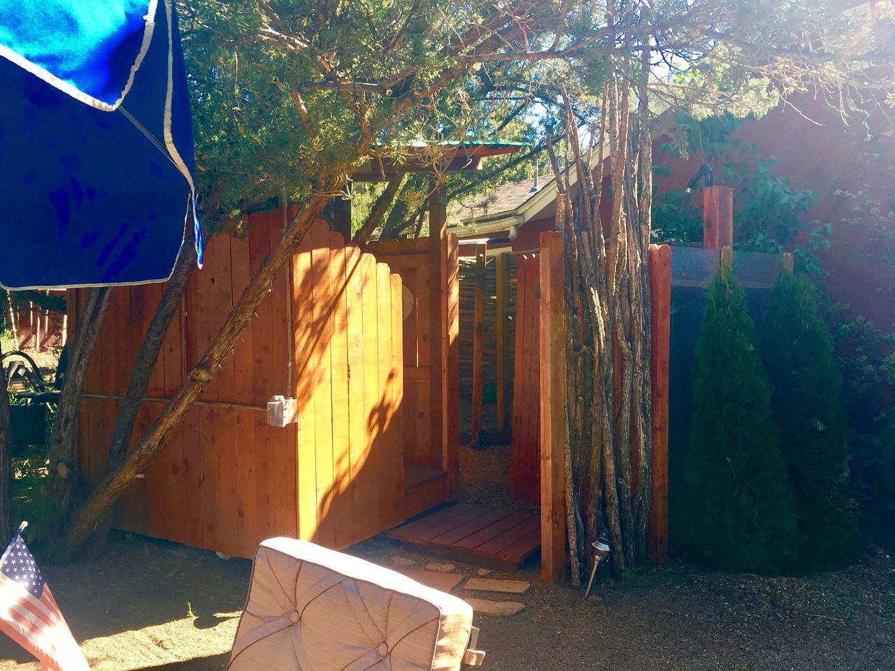 A wooden structure with a door, a small porch, and a covered area with a blue tarp.