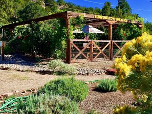 Una pérgola de madera con un letrero que dice 'SUNNYMELLOW VINEYARD' y una bandera estadounidense.