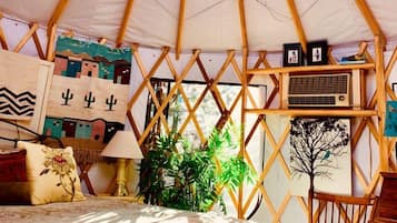 A yurt interior with a bed, a chair, and various wall decorations.