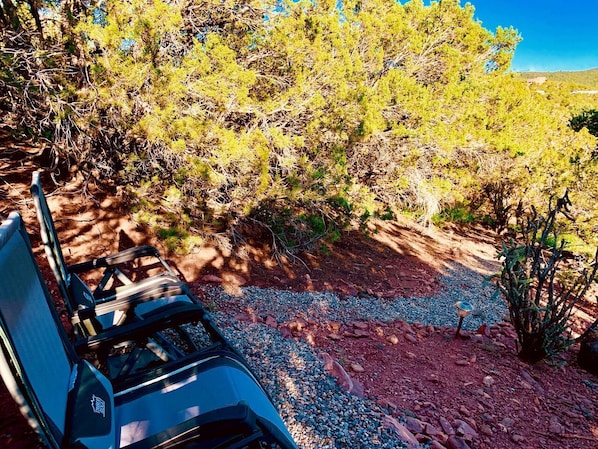 Um camping com cadeira, mesa e chão rochoso com vegetação rala.