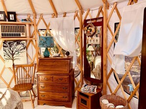 Una habitación acogedora con un aparador de madera, una silla, una mesita y una cesta de mimbre.