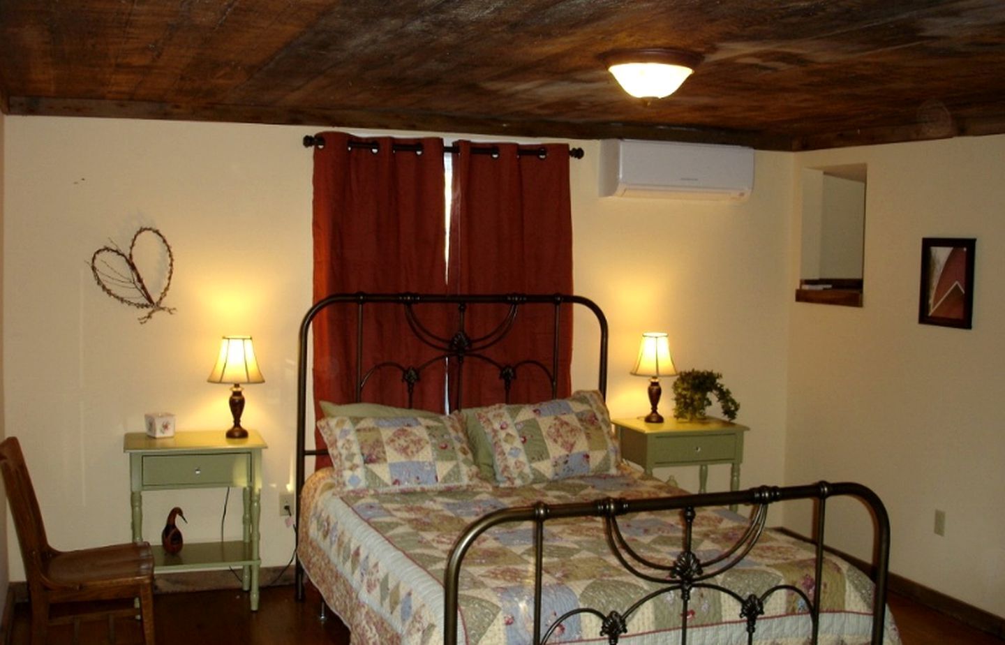 Ein Schlafzimmer mit einem Bett, zwei Nachttischen mit Lampen, einem Sessel, einem Wandspiegel und einer Deckenleuchte.