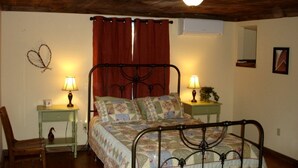 A bedroom with a bed, two bedside tables with lamps, a chair, a wall-mounted mirror, and a ceiling light fixture. - Pre-Civil War Servants' Cottage on Huge Horse and Cattle Farm near Charlottesville, Virginia (Gordonsville)