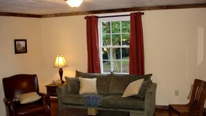 A living room with a sofa, two chairs, a lamp, and a window with curtains. - Pre-Civil War Servants' Cottage on Huge Horse and Cattle Farm near Charlottesville, Virginia (Gordonsville)