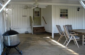 Eine überdachte Veranda mit Grill, Sitzgelegenheiten im Freien und Deckenventilator.