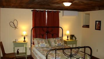 Un dormitorio con una cama, dos mesitas de noche con lámparas, una silla, un espejo en la pared y una lámpara en el techo.