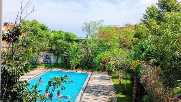 A swimming pool surrounded by lush greenery. - Park Inn Beach Resort (Chennai)