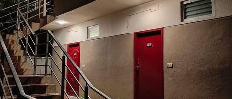 A multi-level building with a staircase, red doors, and potted plants.