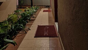 A hallway with a red mat, a staircase, and potted plants. - Park Inn Beach Resort (Chennai)