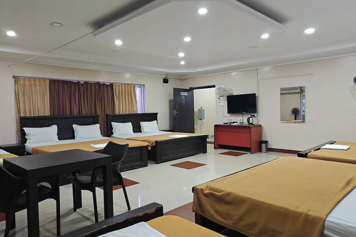A hotel room with two beds, a desk, a chair, a TV, and a mirror.