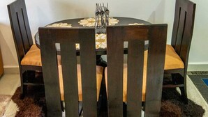 Een ronde eettafel met vier stoelen, een decoratief middelpunt en een bont tapijt op de vloer.