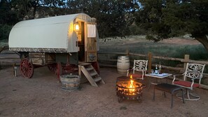 A covered wagon with a fire pit and outdoor seating.