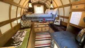 Un interior acogedor de cabaña con una cama, un aparador y una estufa.