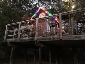 A wooden structure with a balcony, a small porch, and a circular window. - Texas Safari Camp Hummingbird Tree House (Kaufman)