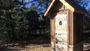 Un comedero de pájaros de madera con techo inclinado y ventana circular.