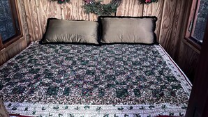 Habitación con paneles de madera, una cama, dos almohadas y tres coronas navideñas en la pared.