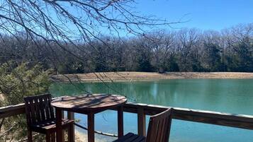 A wooden deck with a table and chairs overlooking a calm lake.