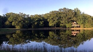 Una propiedad frente al lago con un muelle de madera y una pequeña casa.