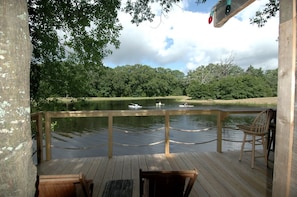 Eine Holzterrasse mit Blick auf einen See und Boote, umgeben von Bäumen.
