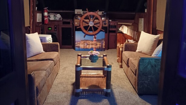A cozy living room with a central coffee table, two sofas, and a decorative wheel. - Hatteras Sleeps 8 & SelfDrive 20' Pontoon Fishing Lobstering Snorkeling Sandbar (Key West)