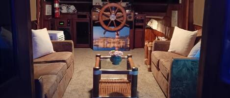A cozy living room with two sofas, a coffee table, and a large wheel wheel in the background.