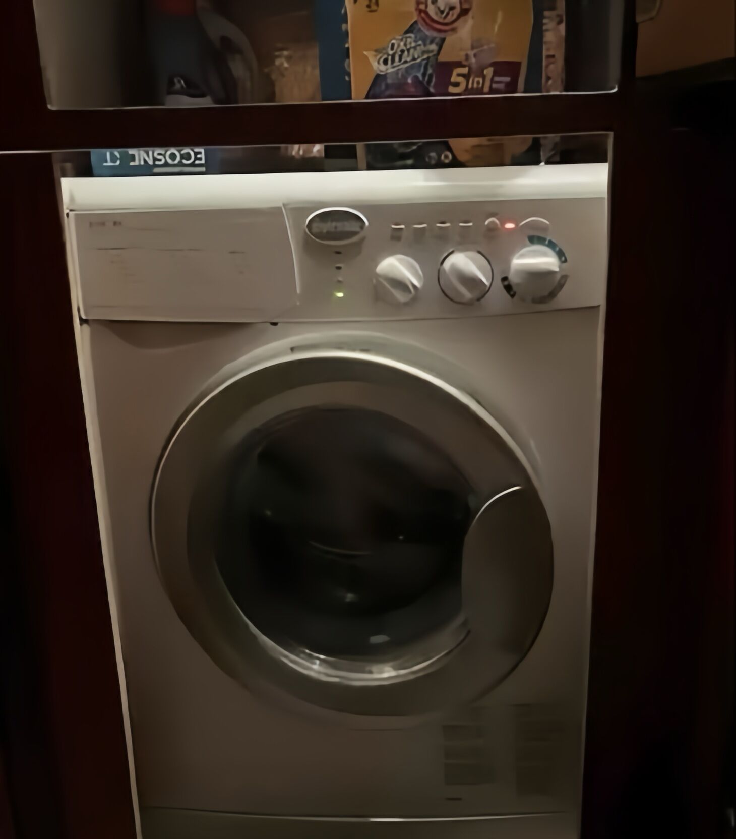 Una lavadora de carga frontal con panel de control, puerta y etiqueta en la parte superior.