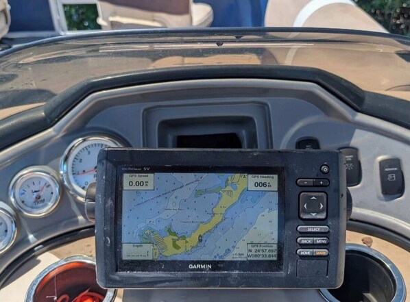 A Garmin GPS device mounted on a vehicle dashboard with speedometer and other gauges.