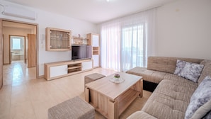Un salon moderne comprenant un canapé, une table basse, un téléviseur et un coin repas.