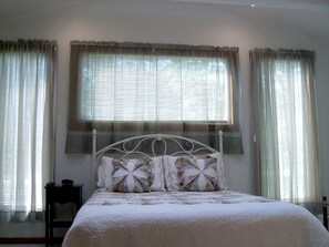 Ein Schlafzimmer mit einem Bett, Vorhängen und einem Fenster.