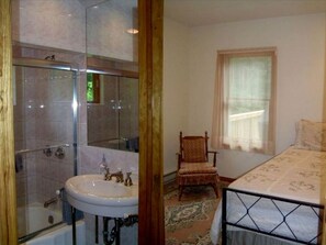Ein Badezimmer mit Duschkabine aus Glas, einem Waschbecken und einem Stuhl.