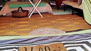 A tent with a bed, a table, and a chair.