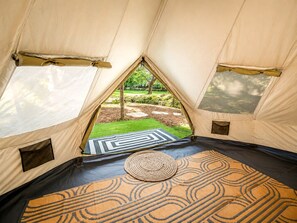 A tent with a view of a garden through a triangular window.