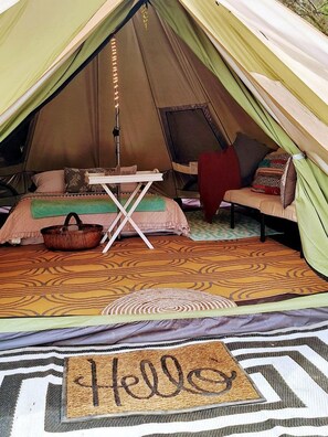 A tent with a bed, a table, and a chair.