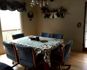 A dining room with a table set for four, blue upholstered chairs, a floral tablecloth, and a decorative wall shelf. - Cabin Getaway near to Pine, Arizona that is Perfect for a Family Vacation (Pine)
