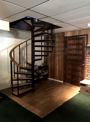 A spiral staircase in a room with a wooden door and a tiled floor.