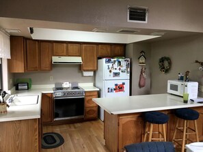 A compact kitchen with wooden cabinets, a stove, a refrigerator, and a microwave.